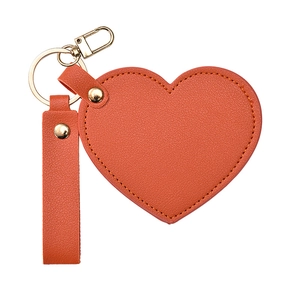 Orange heart leather keychain mirror with gold ring and stitching detail in studio light