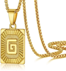 Macro shot of gold square pendant with letter G and radial texture on Cuban chain