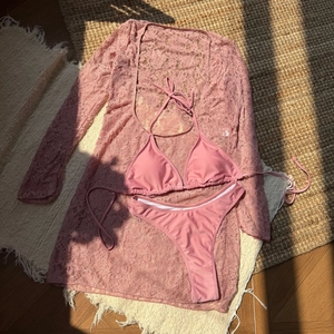 Detailed flat lay of pink three-piece bikini set with long sleeve lace cover-up dress
