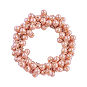 Macro view of elastic hair tie made of vibrant pink pearls with golden thread connections