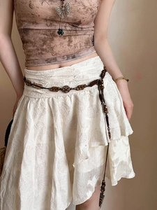 Close-up of vintage beaded waist chain on a white lace skirt with bohemian style aesthetic