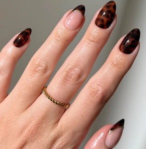 Detail of almond nails with amber leopard patterns and gold-edged French tips