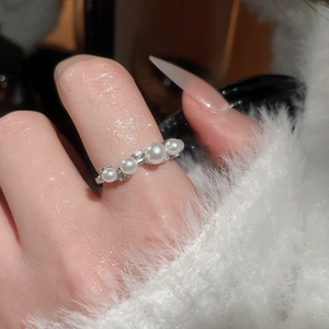 Macro shot of an elegant pearl ring with cubic zirconia on a white mohair background