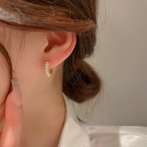 Detailed close-up of a gold C-shaped earring featuring elegant small white pearls