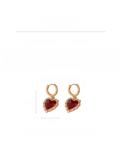 Detail view of gold-plated heart earrings with wine red enamel and cubic zirconia stones