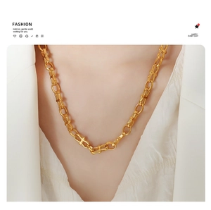 Detail of a gold-plated U-shaped link chain necklace worn on a white suit jacket