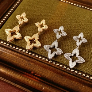 Detail of four-petal flower earrings with gold and silver plating on green velvet