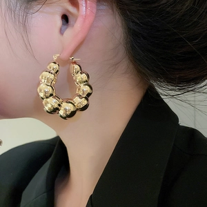 Side view of chunky gold U-shaped hoop earrings with polished spherical link texture