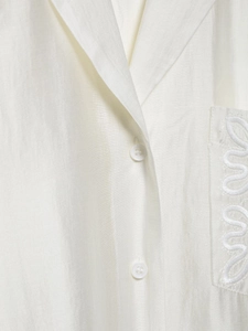 Detailed view of white linen blend shirt featuring premium texture and button craftsmanship