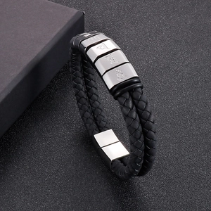 Detail of black braided leather bracelet with silver metal charms and magnetic clasp