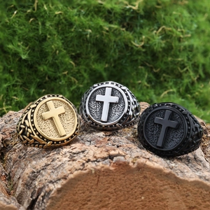 Detailed view of three stainless steel cross rings in gold, silver, and black on wood