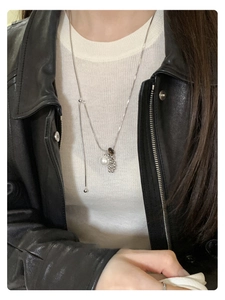 Detail of tiger eye and pearl pendant necklace on model with silver snake chain
