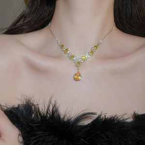 Close-up of a model wearing a gold teardrop pendant necklace with yellow zircon stones