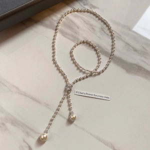 Detail of elegant Y-shaped long pearl necklace with zircon beads on marble background