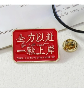 Detail of red enamel badge with gold edges and motivational text on white fabric