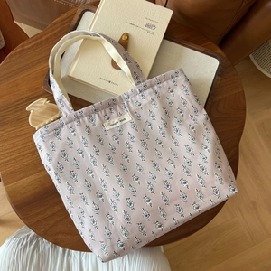 Draufsicht einer fliederfarbenen Baumwolltasche mit schwarzem Blumenmuster auf Holztisch