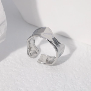 Macro shot of silver irregular wave ring with minimalist open design on stone surface