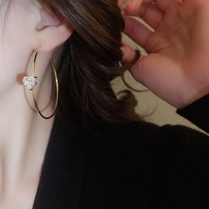 Vue détaillée d'une boucle d'oreille dorée en C avec pierre de zircone en cœur