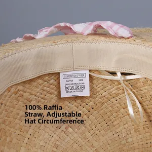 Detail of raffia sun hat featuring pink checkered trim and adjustable inner sweatband