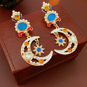 Vintage gold earrings with pearls, blue gems, and moon star enamel on leather gift box