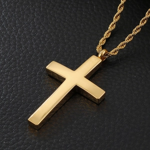 Détail macro d'un pendentif croix dorée avec une chaîne torsadée sur fond en cuir noir