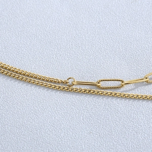 Macro shot of gold layered necklace featuring flat links and oval chain textures