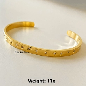 Detail of 5mm gold stainless steel cuff bracelet with star engravings and zircon inlay