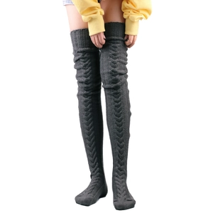 Close-up of dark grey knitted over-knee leg warmers with detailed cable pattern texture