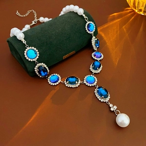 Dettaglio collana con gemme blu e perle su una scatola di velluto verde scuro