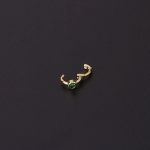 Orecchino a cerchio dorato minimalista con piccolo zircone verde su sfondo nero