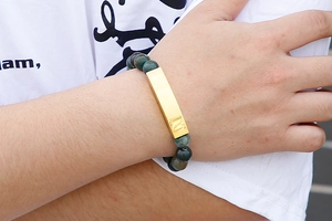 Detail of dark green agate beaded bracelet with an engraved gold rectangular plate