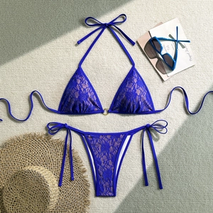 Close-up of deep blue lace bikini with floral patterns and a golden metal ring detail
