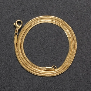 Detail shot of a 2mm golden flat snake chain necklace with lobster clasp on black background
