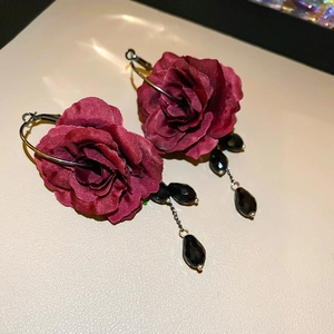 Detailed macro shot of red fabric rose petals and black faceted bead droplet earrings