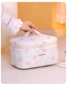 Dettaglio della borsa da trucco trapuntata bianca con fiocchi rosa e maniglia