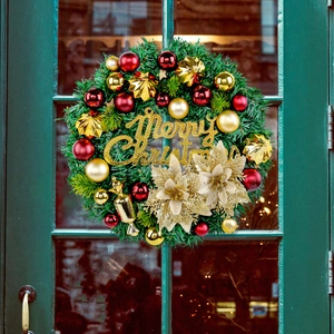 Classic artificial Christmas wreath with red ornaments and golden poinsettia on a green door