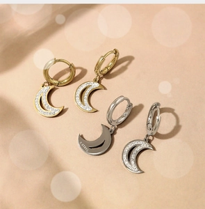 Macro detail of crescent moon earrings in gold and silver steel with inlaid zircons