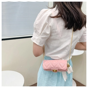 Close-up of pink quilted cylindrical bag with gold chain strap on female model