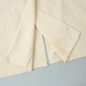 Detailed macro view of cream linen dress hemline with high-quality stitching detail
