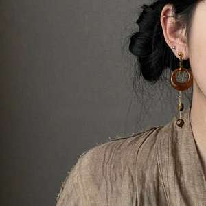Detail showing vintage resin tiger eye asymmetric drop earring worn by a model