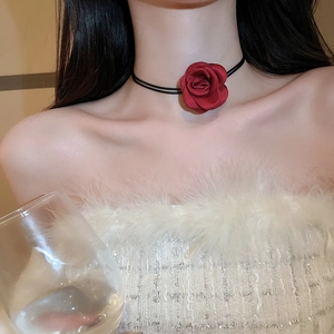 Detail of red fabric rose necklace with black double cord on model wearing white feathers