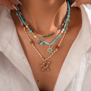 Détail d'un collier bohème multicouche avec perles bleues, pendentif soleil et tissage