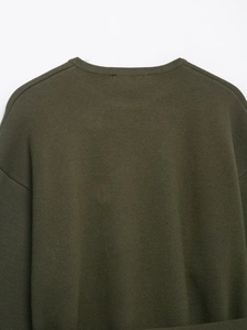 Nahaufnahme des olivgrünen Strickpullovers mit Fokus auf Textur und Halsausschnitt