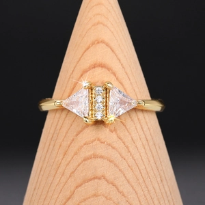 Macro shot of geometric triangle zircon ring on a wood stand with gold plating detail