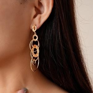 Close-up of golden multi-layered geometric hoop earrings with textured finish on model