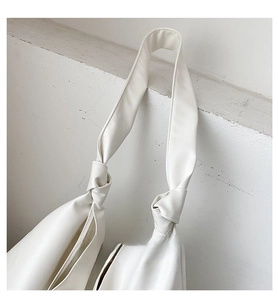 Close-up of flexible white PU leather shoulder bag featuring unique knotted strap detail