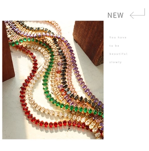 Macro detail of colorful oval-cut crystal tennis necklaces in gold claw settings