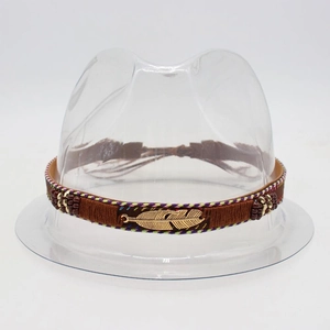 Detail of a brown woven straw hat band with golden metal feathers and colorful beads