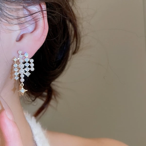Detail of elegant star and pearl stud earrings with sparkling crystals on model's ear