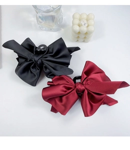 Detail of large black and wine red satin bow hair claws on a clean white background